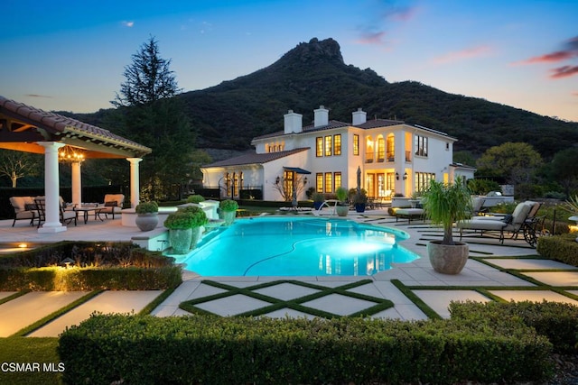 pool at dusk with a mountain view and a patio area