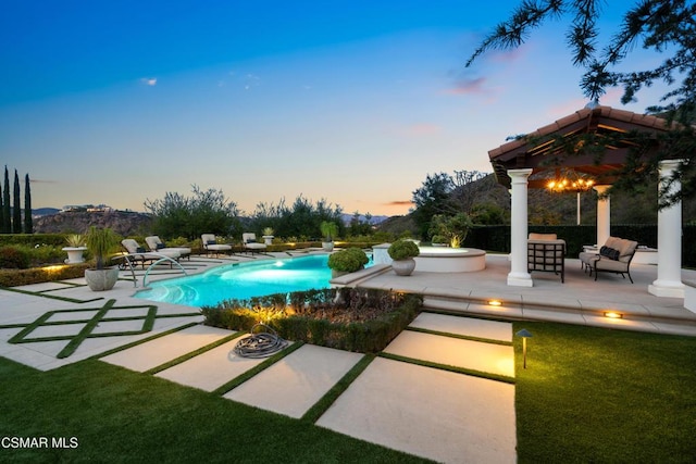 pool at dusk featuring a patio area and a lawn