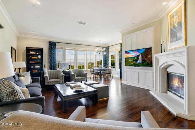 living room featuring a notable chandelier, dark wood-type flooring, and ornamental molding