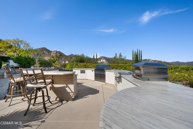 view of patio with exterior kitchen, a mountain view, area for grilling, and an outdoor bar