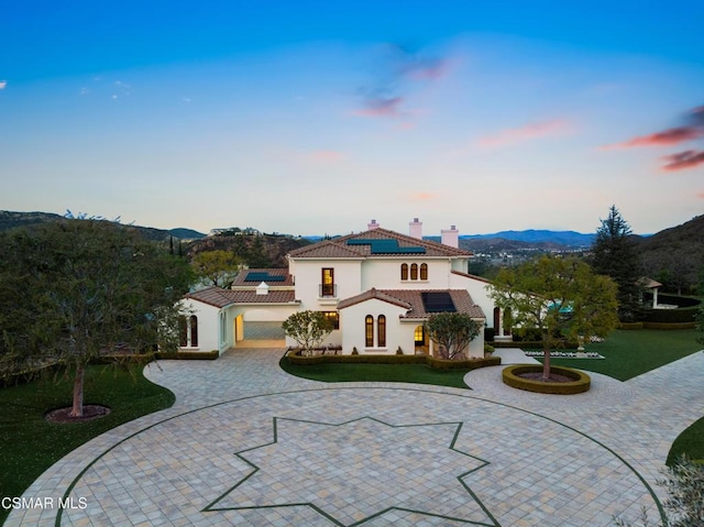 mediterranean / spanish house with a yard, a mountain view, and solar panels