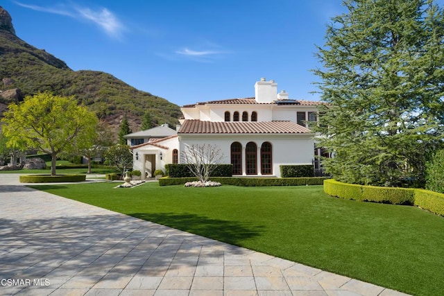 rear view of property with a mountain view and a lawn