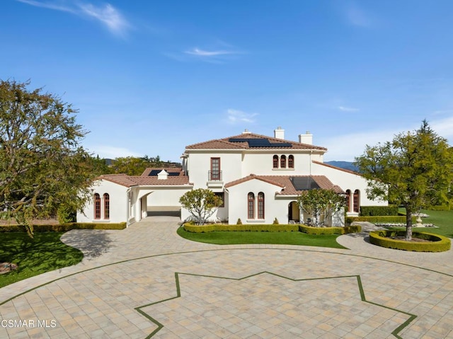 mediterranean / spanish-style house with a garage, a front yard, and solar panels