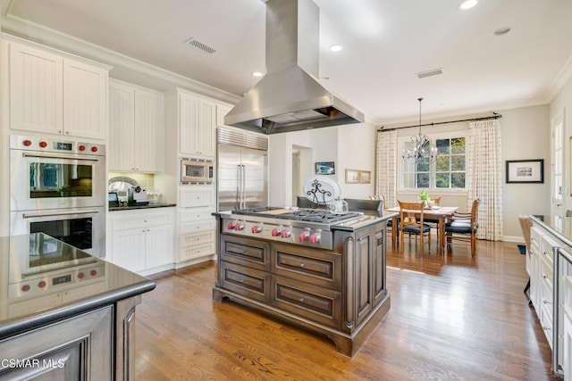 kitchen with white cabinetry, island exhaust hood, built in appliances, and an island with sink