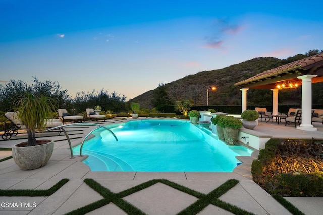 pool at dusk with a mountain view and a patio