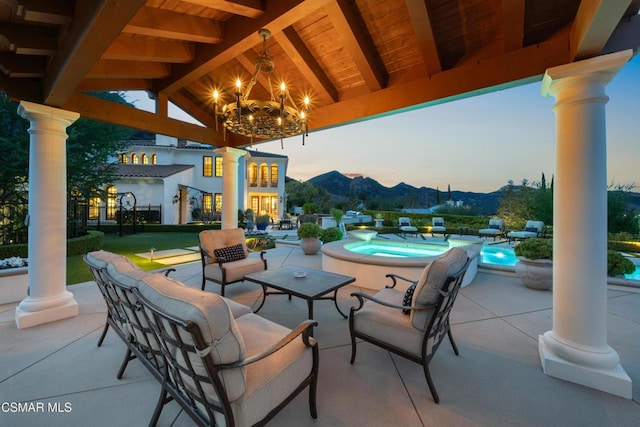 patio terrace at dusk with a gazebo, a swimming pool with hot tub, and a mountain view