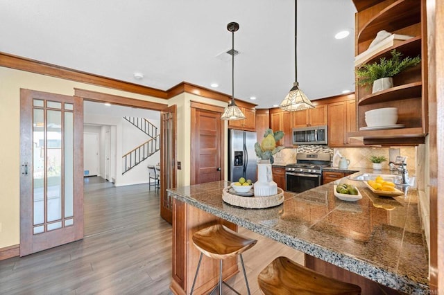 kitchen featuring sink, appliances with stainless steel finishes, a kitchen breakfast bar, decorative light fixtures, and kitchen peninsula