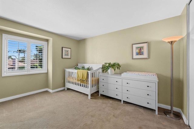 bedroom featuring light carpet and a nursery area