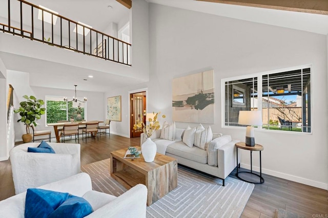 living room with high vaulted ceiling, hardwood / wood-style floors, and a chandelier