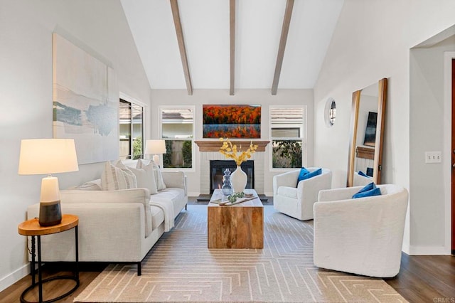 living room featuring plenty of natural light, hardwood / wood-style floors, beam ceiling, and a brick fireplace