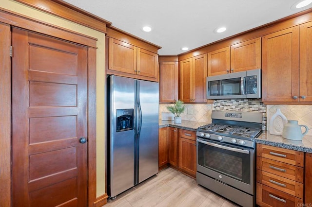 kitchen featuring stainless steel appliances, stone countertops, and backsplash