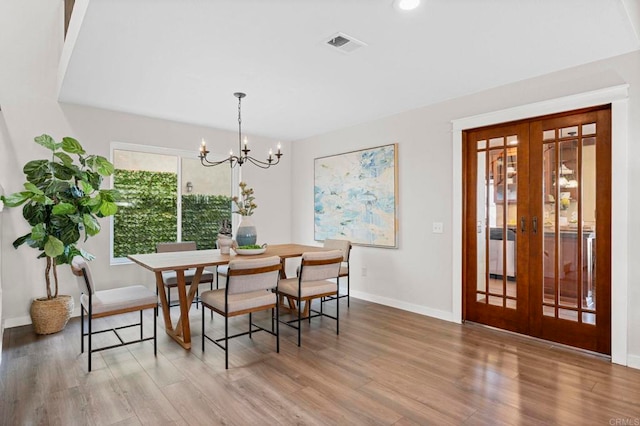 dining space with french doors, a notable chandelier, and hardwood / wood-style flooring