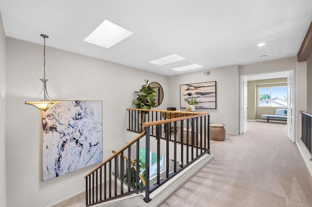 corridor featuring a skylight and light colored carpet