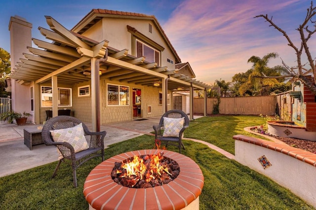 back house at dusk with a patio, a pergola, a yard, and an outdoor fire pit