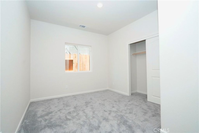 unfurnished bedroom with light carpet and a closet