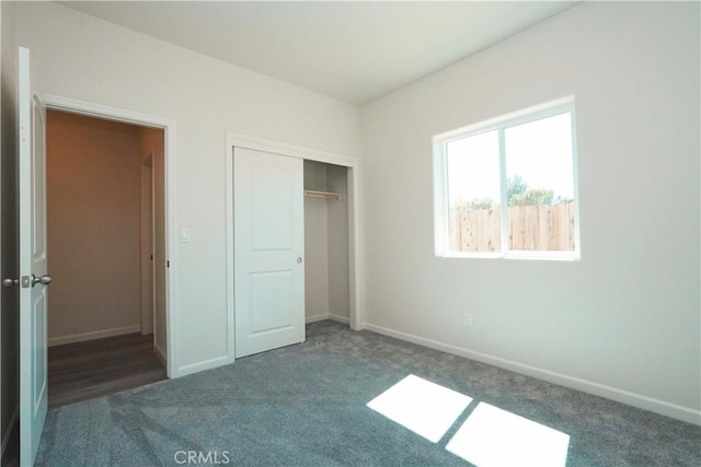 unfurnished bedroom featuring dark carpet and a closet