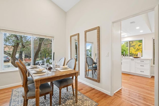 dining space featuring high vaulted ceiling and light wood-type flooring