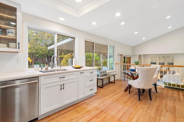 kitchen with lofted ceiling, sink, white cabinetry, stainless steel dishwasher, and light hardwood / wood-style floors