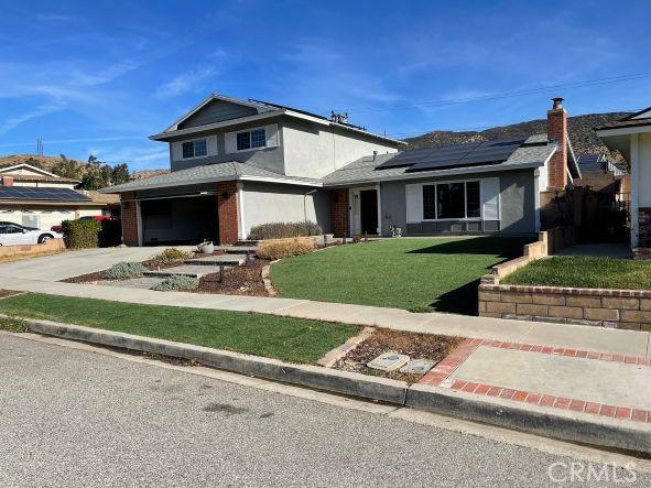 view of front of house with a garage, a front lawn, and solar panels