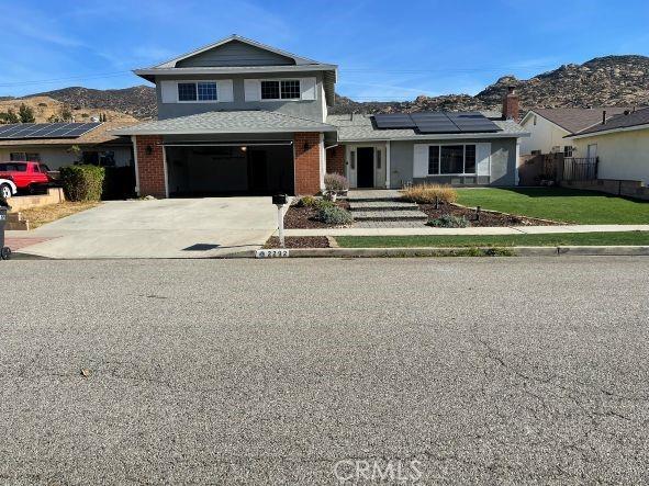 front facade featuring a garage, a mountain view, and solar panels