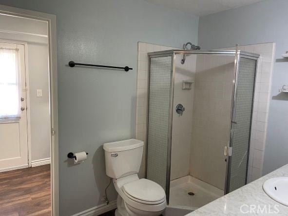 bathroom featuring walk in shower, vanity, toilet, and wood-type flooring