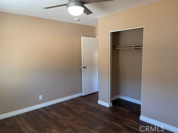 unfurnished bedroom with ceiling fan, dark hardwood / wood-style floors, and a closet