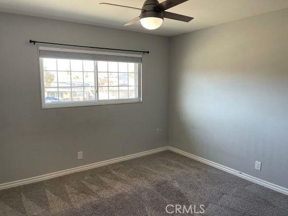 carpeted spare room with ceiling fan