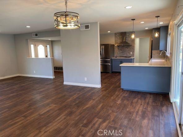 kitchen featuring sink, stainless steel fridge, hanging light fixtures, dark hardwood / wood-style floors, and wall chimney exhaust hood