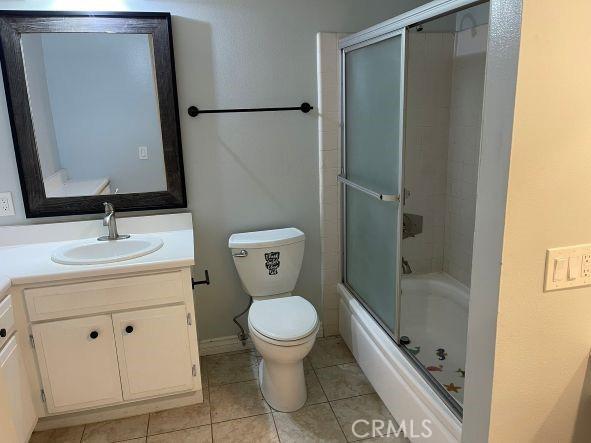 full bathroom featuring vanity, tile patterned flooring, enclosed tub / shower combo, and toilet