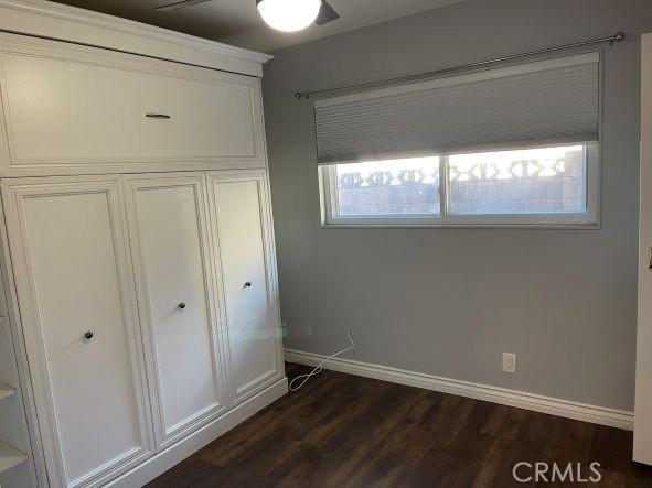 unfurnished bedroom with dark wood-type flooring, a closet, and ceiling fan