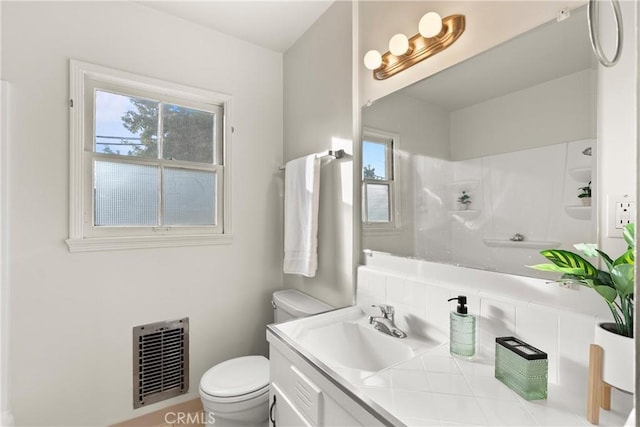 bathroom featuring vanity, toilet, and a shower