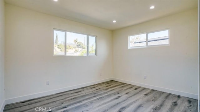 spare room featuring light hardwood / wood-style flooring and a healthy amount of sunlight