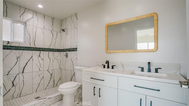 bathroom with a tile shower, vanity, plenty of natural light, and toilet