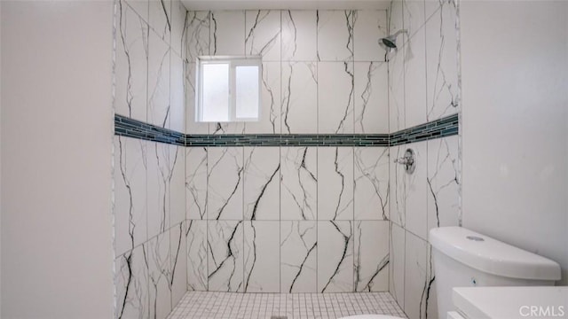 bathroom featuring tiled shower and toilet