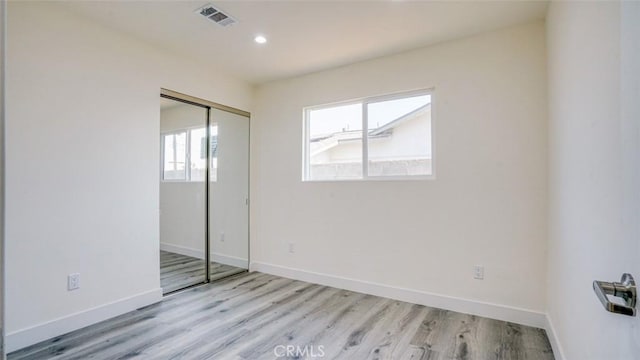 unfurnished bedroom featuring light hardwood / wood-style floors and a closet