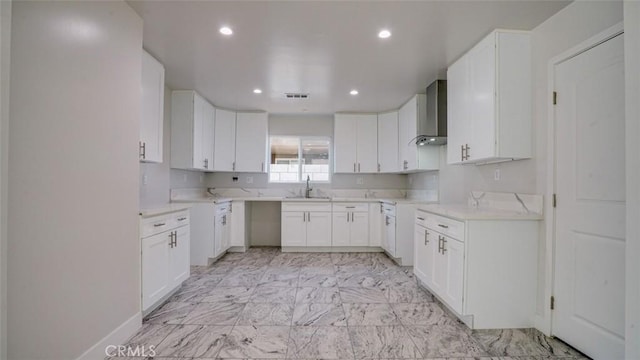 kitchen with white cabinetry, wall chimney range hood, and sink