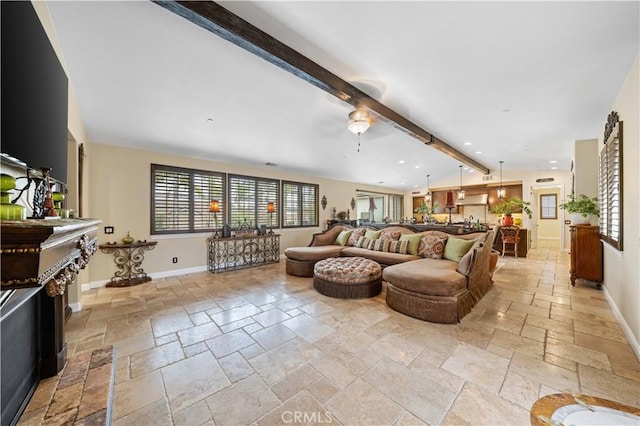 living room featuring lofted ceiling with beams, a fireplace, stone tile flooring, and baseboards