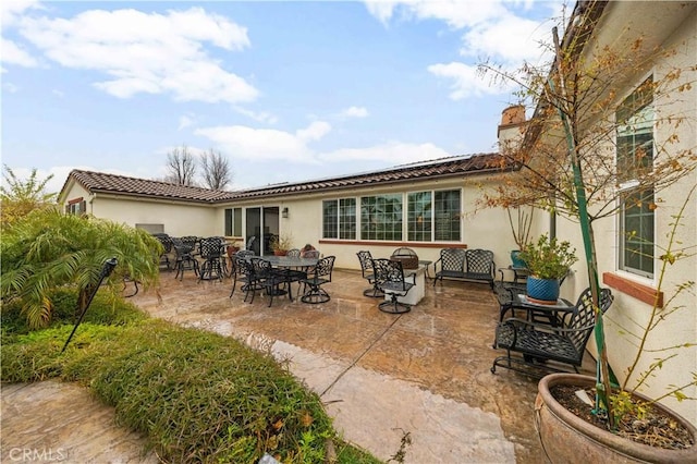 back of house featuring a patio, outdoor dining area, a tiled roof, and stucco siding