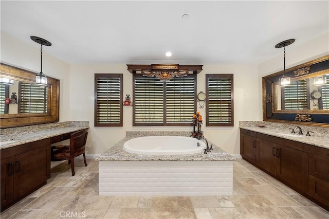 full bath featuring a healthy amount of sunlight, vanity, baseboards, and a bath