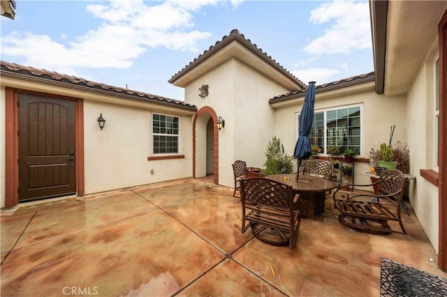 exterior space with a tiled roof, outdoor dining space, a patio area, and stucco siding