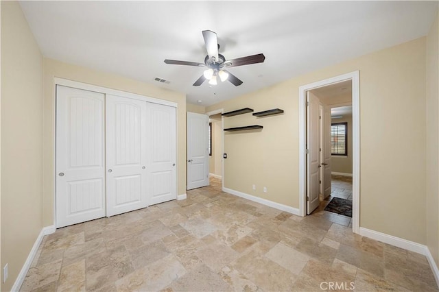 unfurnished bedroom with visible vents, baseboards, ceiling fan, stone finish floor, and a closet