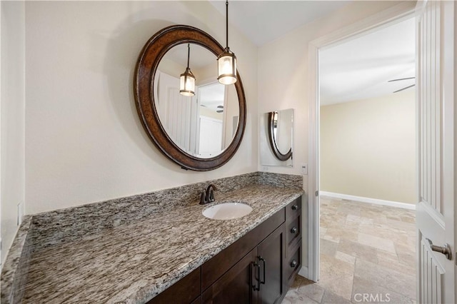 bathroom featuring stone finish flooring, baseboards, and vanity