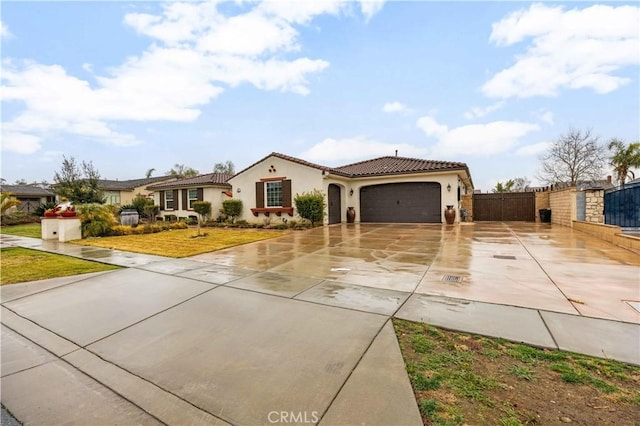 mediterranean / spanish home featuring a garage, concrete driveway, a tiled roof, fence, and stucco siding