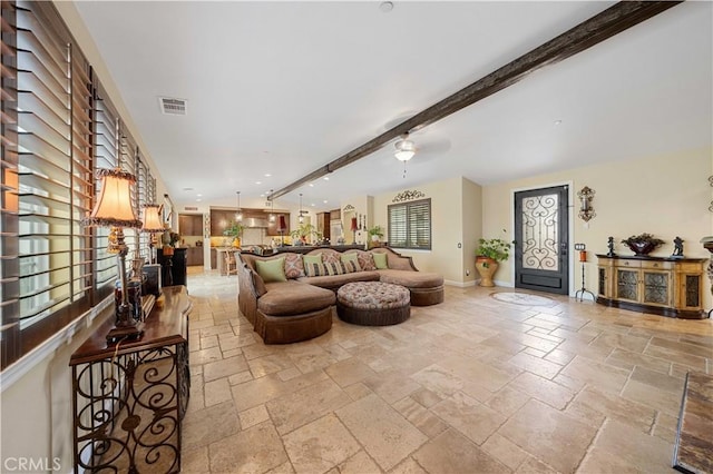 living room featuring stone tile floors, visible vents, and a wealth of natural light