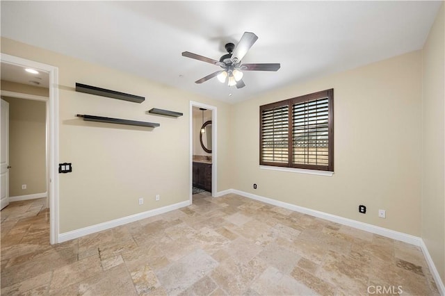 spare room with stone finish floor, ceiling fan, and baseboards