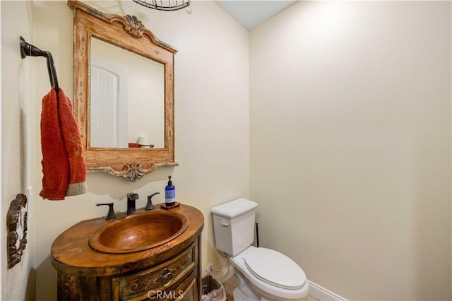 half bath with vanity, toilet, and baseboards