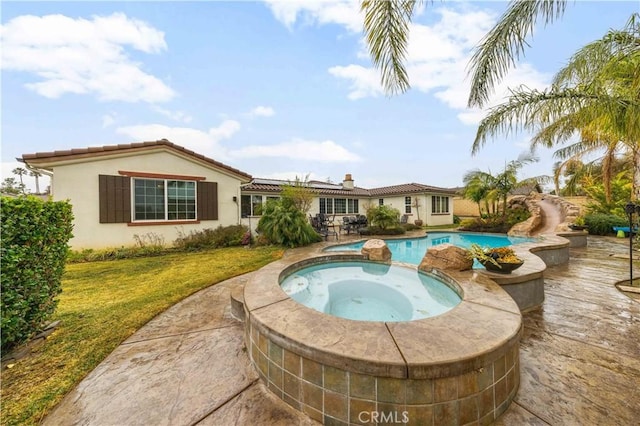 view of pool with a pool with connected hot tub, a lawn, and a patio