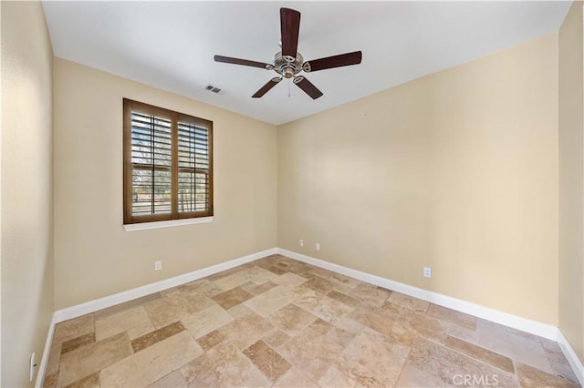 empty room featuring stone tile flooring, visible vents, ceiling fan, and baseboards