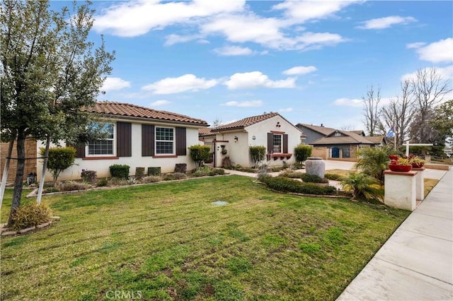 mediterranean / spanish house featuring a tile roof, a front yard, and stucco siding