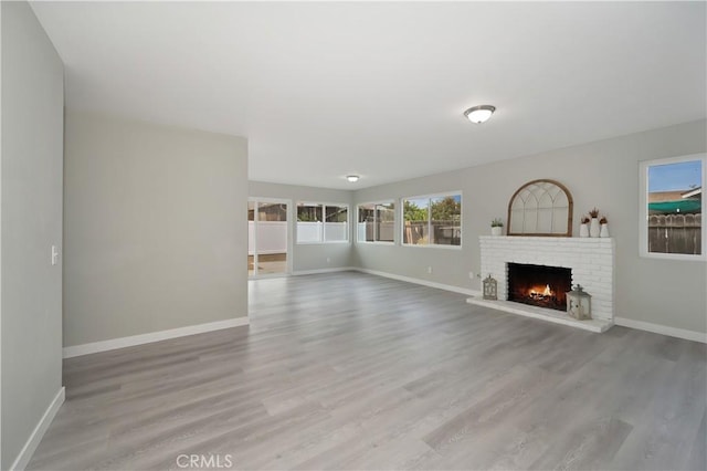 unfurnished living room featuring a fireplace, baseboards, and wood finished floors